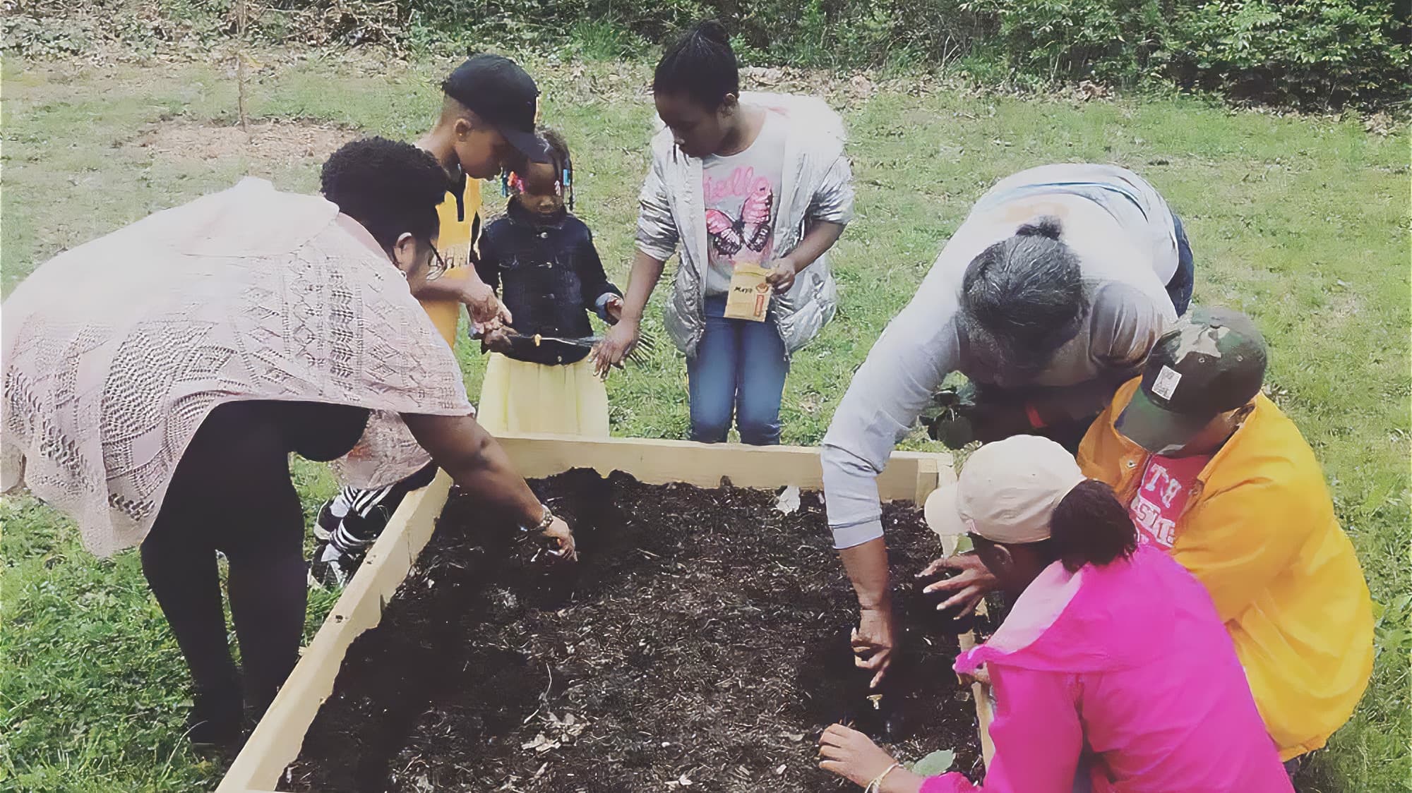 a group of adults and children gardening